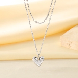Détail du collier argenté à deux rangs avec pendentif cœur à texture pointillée