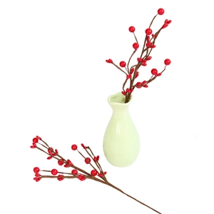 Detail showing artificial red berries branch in a ceramic vase for festive home decoration