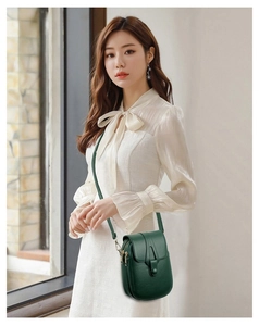 Detail of dark green lychee leather mini crossbody bag with multiple zip pockets on model