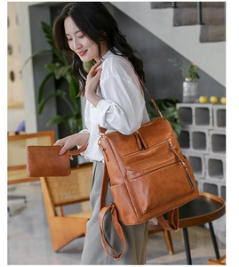 Brown PU leather backpack and matching pouch shown in a soft indoor cafe setting