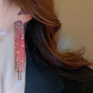 Detailed view of pink gradient crystal tassel earrings worn with a black blazer