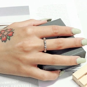 Detail eines silbernen Bambus-Rings aus Titanstahl, getragen über einer Geschenkbox