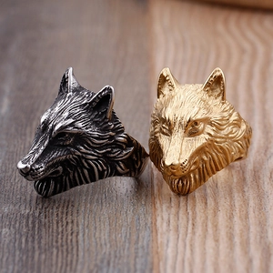 Vintage gothic wolf head rings in silver and gold finishes on a rustic wood background