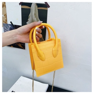Detail of yellow crocodile pattern mini square bag with gold chain and top handles