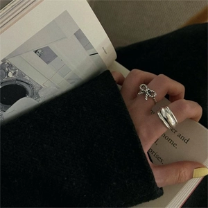 Detail of a 925 sterling silver bow knot ring and a wide band on a model's hand