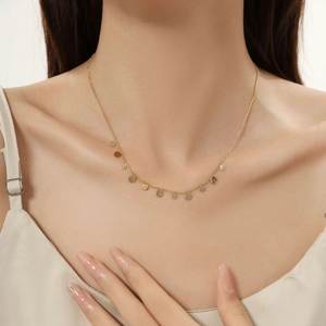 Primo piano della collana con ciondolo a disco placcato oro 18K indossata da una modella