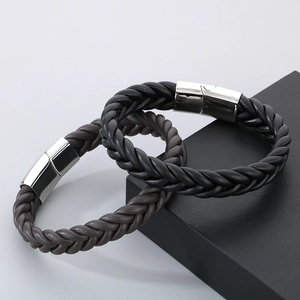 Detail of black and dark brown braided leather bracelets with polished magnetic metal clasps