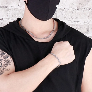 Gros plan d'un ensemble collier et bracelet gourmette argenté porté par un modèle