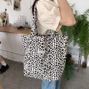 Close-up of leopard print canvas tote bag carried by a model in a cozy interior cafe setting