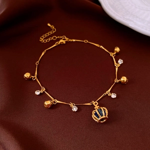 Vue macro du bracelet doré avec grelots et pendentif couronne serti de gemme bleue