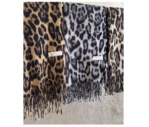 Three leopard print scarves in brown and grey hanging with soft tassels and quality labels