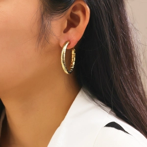 Macro shot of large golden hoop earrings featuring a sophisticated spiral textured surface