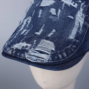 Vintage navy blue distressed denim flat cap with ripped details and worn-out texture