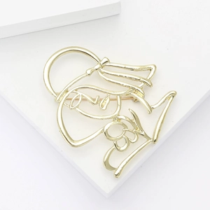 Minimalist gold hollow silhouette brooch displayed on white geometric studio props