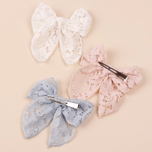 Detailed view of three lace bow hair clips in white, pink, and blue with metal duckbill clips