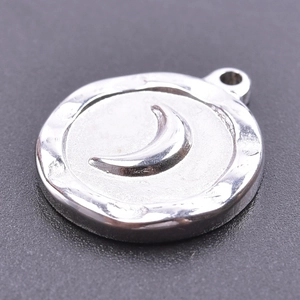 Macro detail of round silver crescent moon pendant with hammered metal texture finish