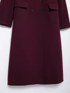 Détail d'un manteau long bordeaux avec de grandes poches à rabat et boutons ronds