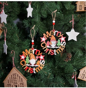 Close-up of wooden Merry Christmas ornaments featuring a gnome and tree on a holiday pine branch