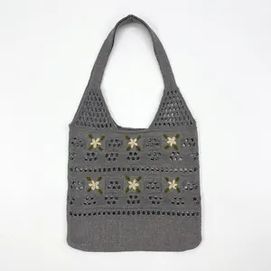 Close-up of grey knit tote bag featuring hollow texture and yellow floral embroidery