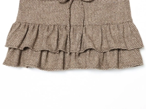 Dettaglio del tessuto in tweed marrone a spina di pesce con elegante orlo a balze