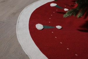 Gros plan sur le cache-pied de sapin tricoté rouge et beige avec pompons blancs