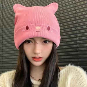 Close-up of pink knitted hat with cute cat ears and minimal animal embroidery detail