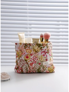 Vintage floral jacquard makeup bag with brushes and skincare products on a desk