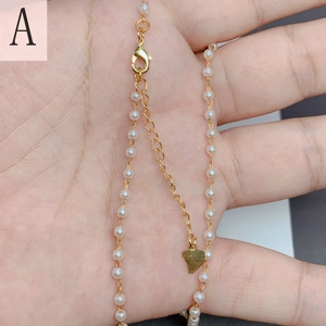 Close-up of a 18K gold plated pearl necklace with a heart pendant held in hand