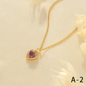 Close-up of heart-shaped purple gemstone pendant necklace on gold cuban chain
