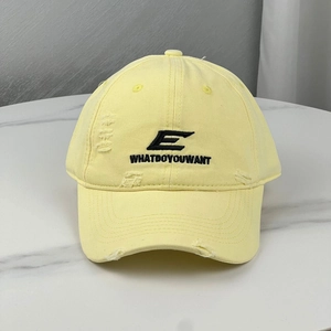 Macro shot of embroidered letters and distressed fabric details on a yellow baseball cap