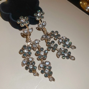 Detail of vintage gold flower tassel earrings featuring teal and white crystal rhinestones