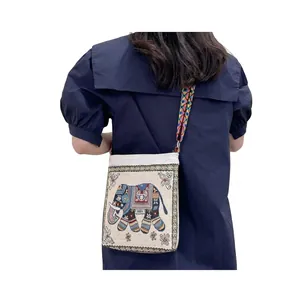 Detailed view of Southeast Asian elephant embroidery on a cream canvas crossbody bag