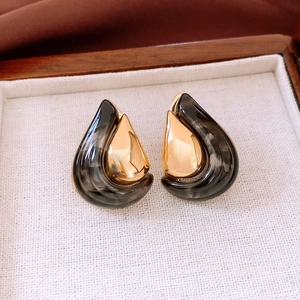 Macro shot of 18K gold plated resin teardrop earrings in a wooden jewelry box