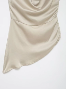 Vue détaillée du tissu en satin champagne avec ourlet asymétrique et drapé élégant de luxe