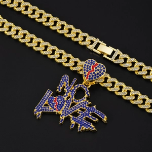 Macro detail of gold Cuban link necklace with blue rhinestone NO LOVE pendant