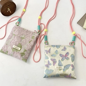 Detail of floral and butterfly jacquard mini bags with adjustable woven shoulder straps