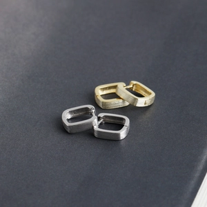 Detail of gold and silver rectangular hoop earrings featuring a brushed metal texture finish