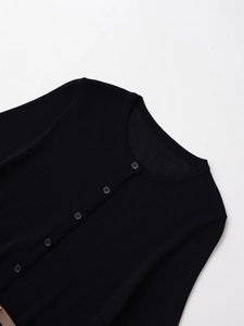 Detail of classic black knit cardigan featuring fine ribbing and grey front buttons
