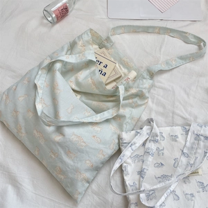 Detail of cute cat printed canvas tote bags in blue and white on a cozy bed