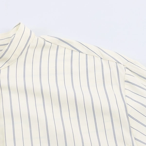 Detailed view of the mandarin collar and blue striped pattern on cream woven fabric