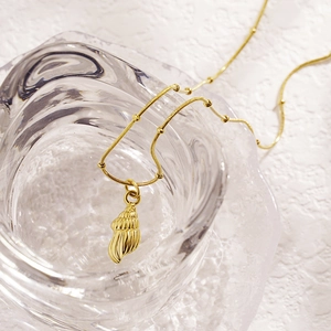 Artistic detail of a gold conch pendant on a sleek snake chain over glass décor