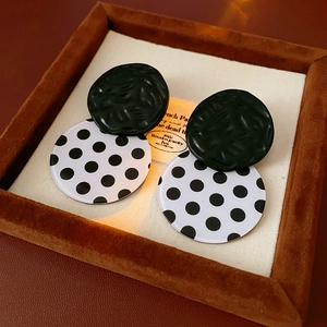 Close-up of black and white polka dot acrylic earrings on a velvet display tray