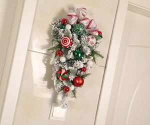 Detail of flocked Christmas teardrop swag with red bows and colorful ornaments on a wall