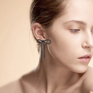 Detail of elegant black rhinestone bow earrings with long tassel chain on model