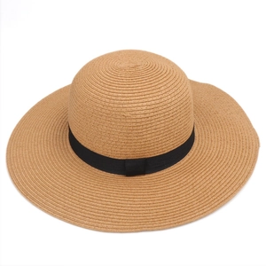 Detailed texture of brown straw sun hat with minimalist black ribbon decoration