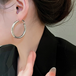 Close-up of polished silver hoop earrings on a model wearing a professional black suit