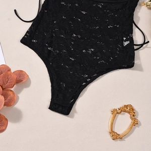 Close-up of black lace bodysuit with intricate hollow-out floral patterns and mesh texture