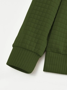 Detail of dark army green waffle knit fabric and ribbed cuff on a men's henley sweatshirt