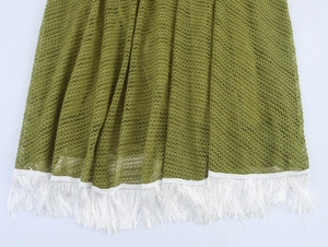 Detail of army green mesh knit fabric with dense white fringe trim on the dress hem