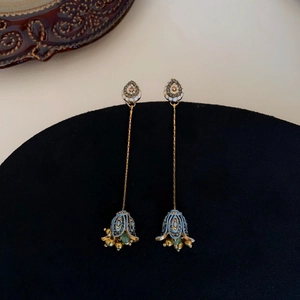 Detail of vintage flower earrings with blue enamel, crystals, and long tassel pendants